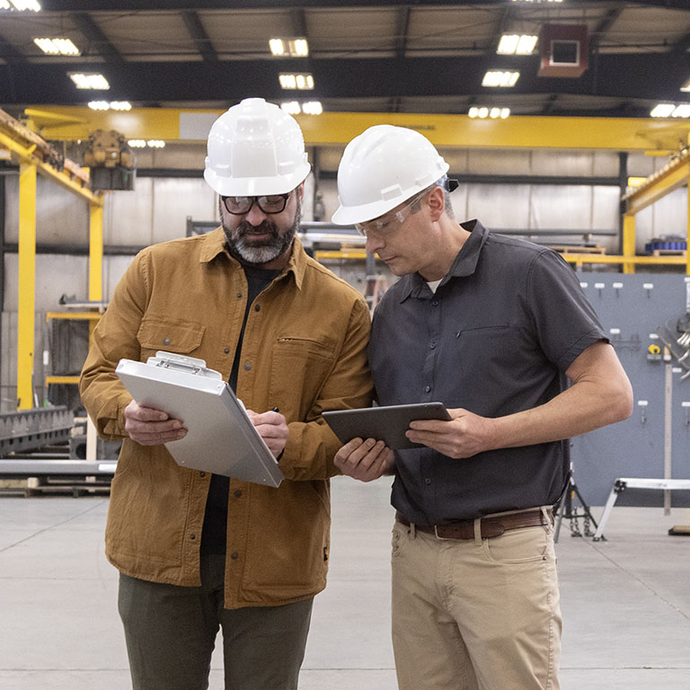 Two men looking over plans in a manufacturing facility