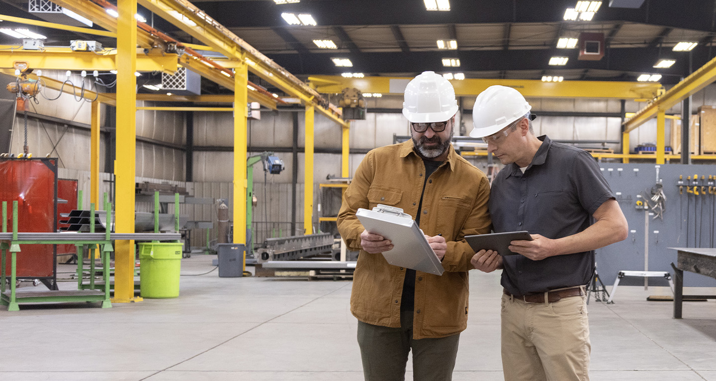 Two men looking over plans in a manufacturing facility