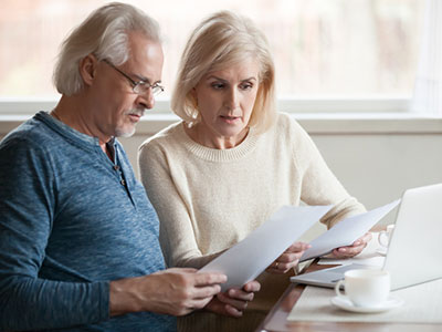 Older couple reviewing bills in front of laptop