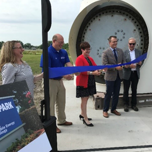 MidAmerican and DMACC representatives cutting a blue ribbon in front of the donated nacelle on the DMACC campus.