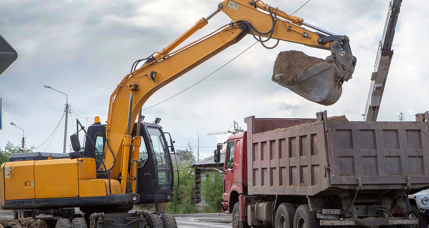 An excavator and a dump truck working near power lines