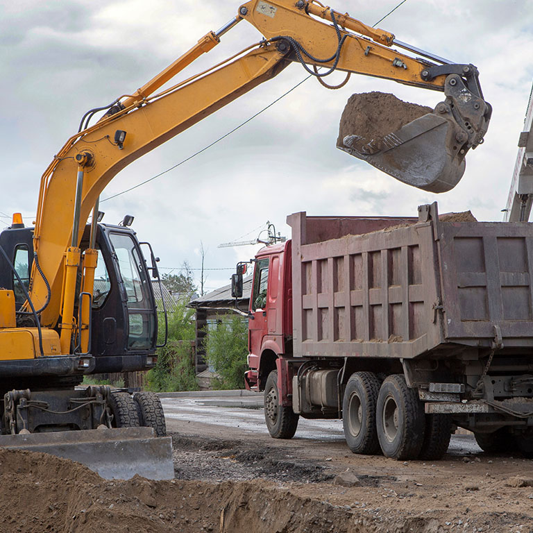 An excavator and a dump truck working near power lines