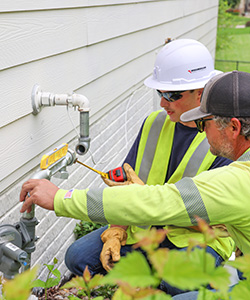 Two MidAmerican employees measuring a natural gas line as part of a residential meter replacement project