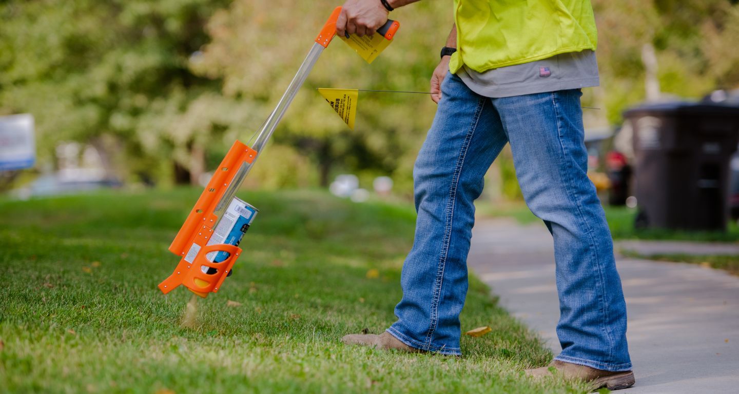 Employee marks a yard with spray paint indicating underground pipelines