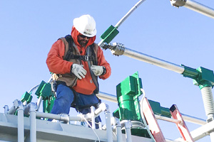 A MidAmerican employee wearing gloves, hardhat and safety glasses installs GreenJacket animal protection devices on a substation.