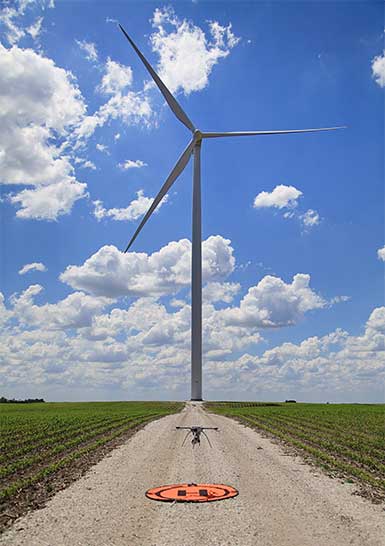 Drone landing on it's pad in front of a wind turbine