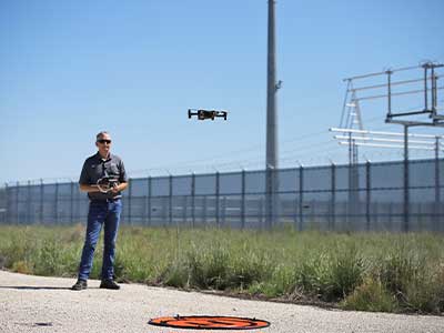 Employee piloting a drone from gravel road
