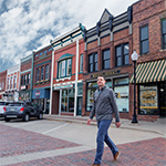 A man walking across the street of a small town business district