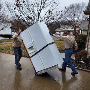 two employees moving a refrigerator in a residential area