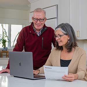 couple looking at a computer holding a bill