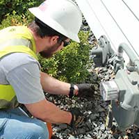 MidAmerican employee looking and fixing a gas meter on a house