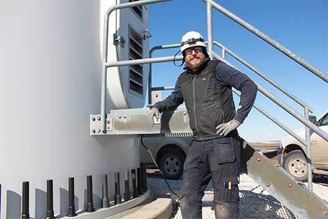 Jason Gruszeczka standing next to the entry way to a wind turbine