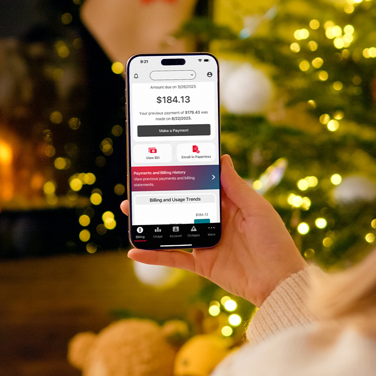 closeup of a hand holding a smartphone displaying the billing screen of the MidAmerican Energy app