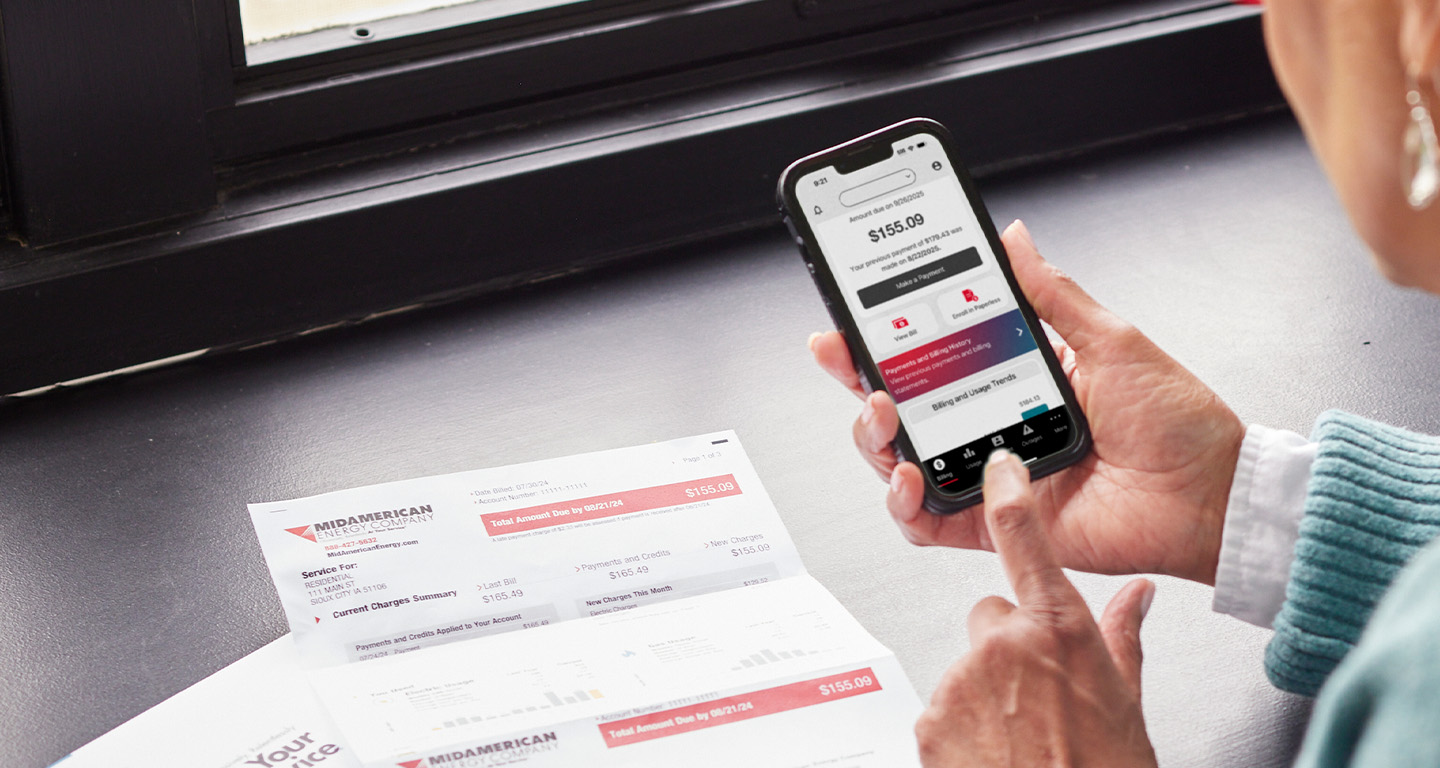 closeup of a hand holding a smartphone displaying MidAmerican Energy's outage map