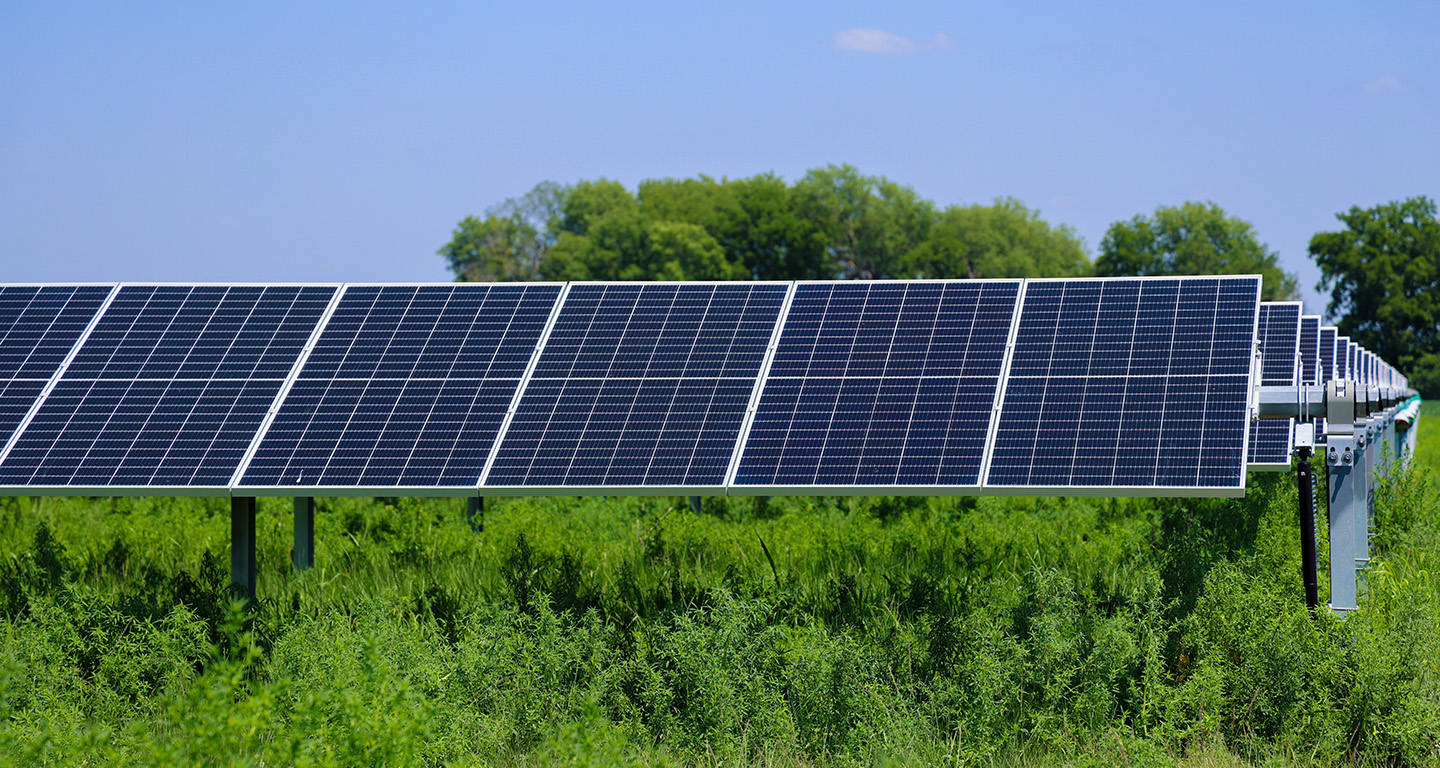 Solar panel array in a grassy field under a clear sky