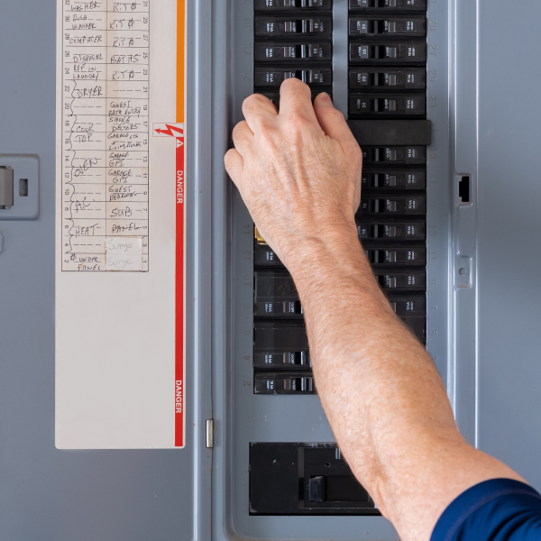 Person adjusting circuit breakers in their home electrical panel
