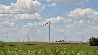 Several wind turbines set against blue sky, white fluffy clouds