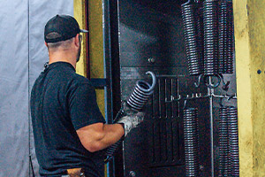 An employee of Iowa Spring carrying a large spring to a mounted rack.
