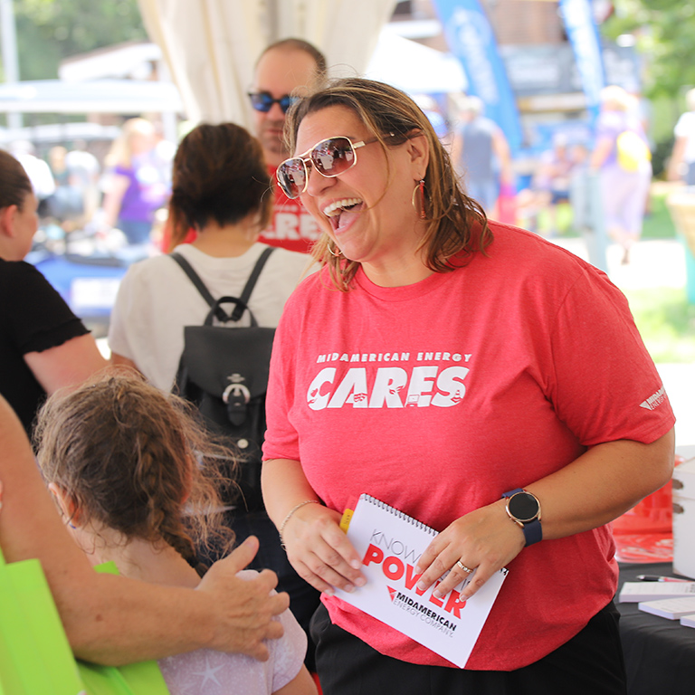 A MidAmerican CARES volunteer talking with a family at the Iowa State Fair