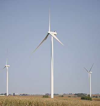 Three wind turbines standing in a field against a clear sky