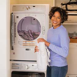Woman folding clothes in front of a dryer