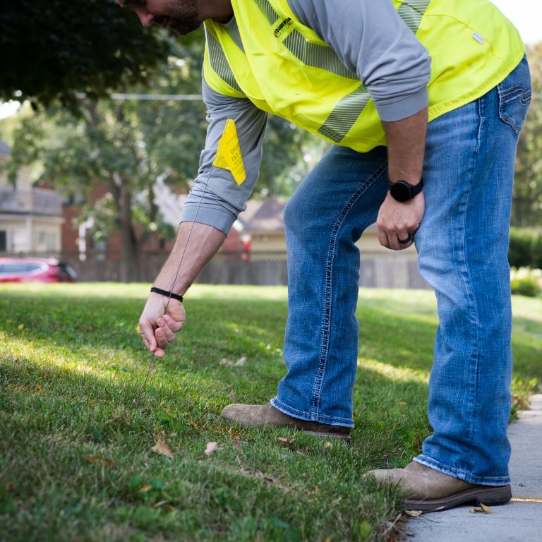 Gas employee pushes in yard flag to mark underground pipelines