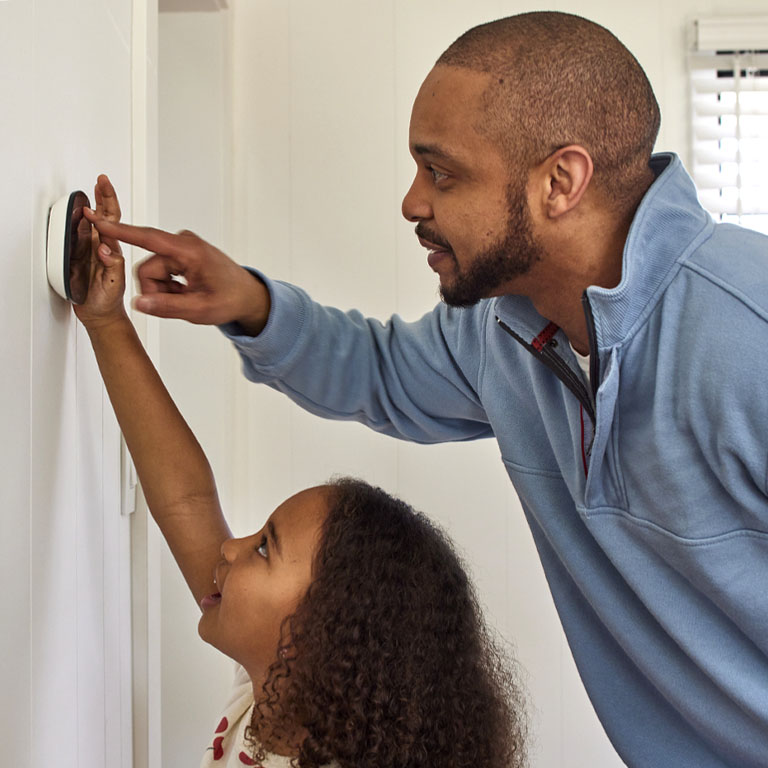 Black father and daughter using a smart thermostat