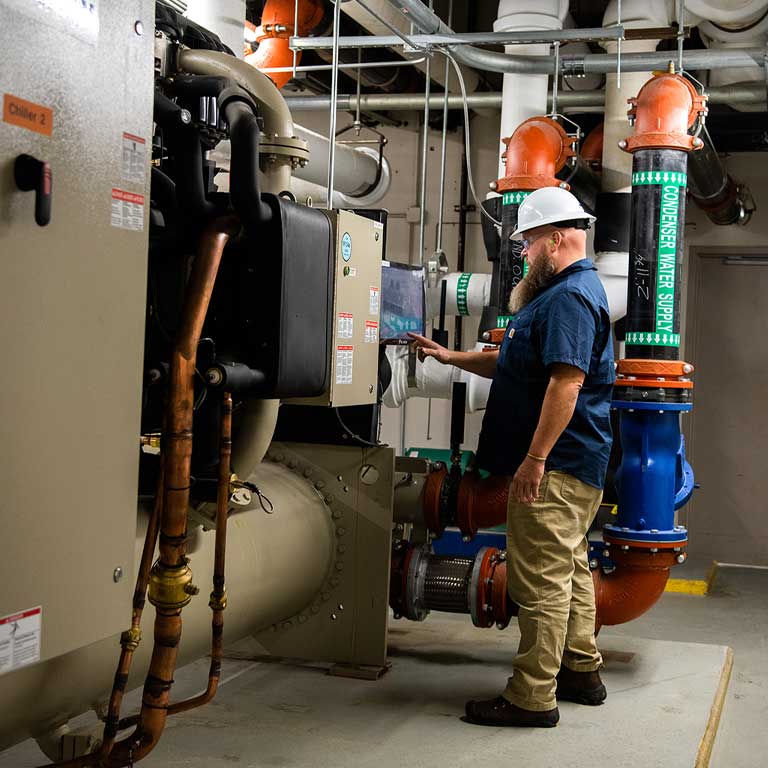 Facilities employee adjusts large HVAC system