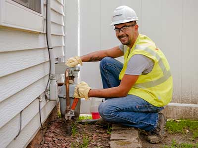 A gas technician tightens a bolt on a natural gas meter