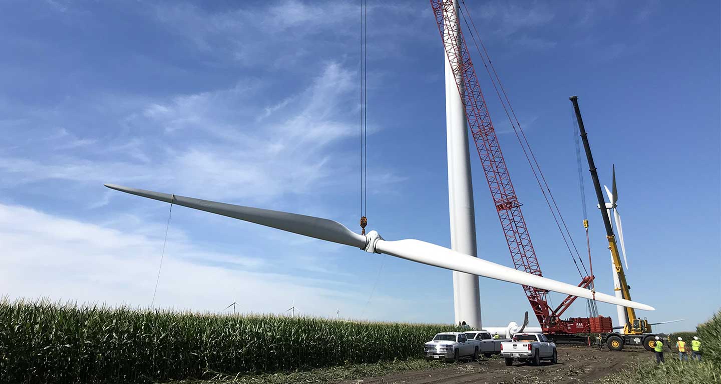 Red crane lifting wind turbine blade