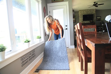 Woman clearing rug from floor register 