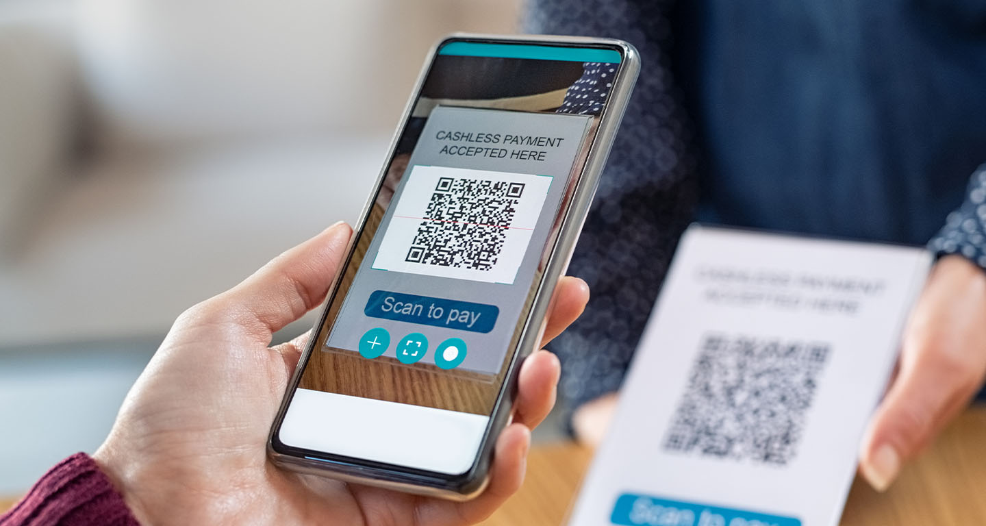 Close photo of a hand holding a smartphone displaying a QR code as it scans the code on a card being held up.