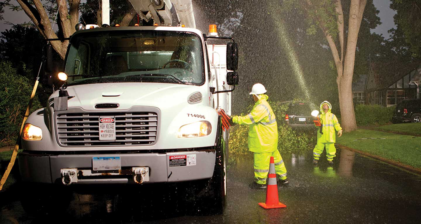 MidAmerican employees working in severe weather by a truck with fallen branches