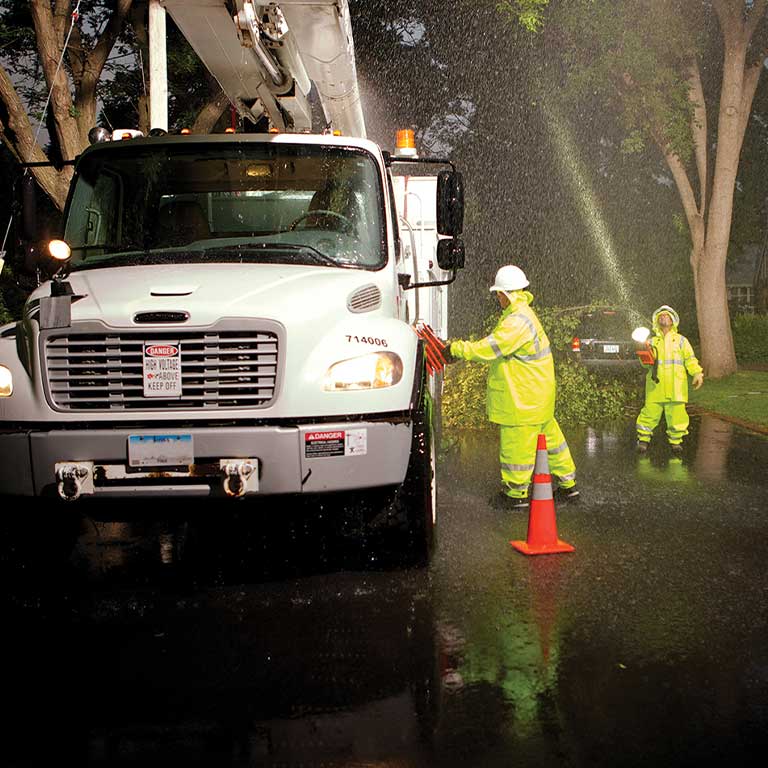 MidAmerican employees working in severe weather by a truck with fallen branches