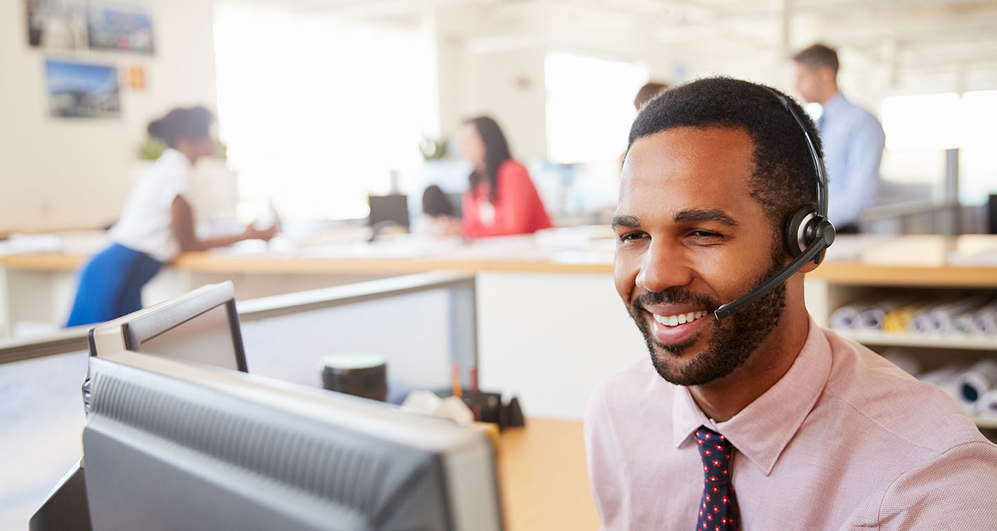 A young man attending a virtual meeting in a small office