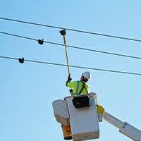 MidAmerican employee installing a smart sensor on a power line