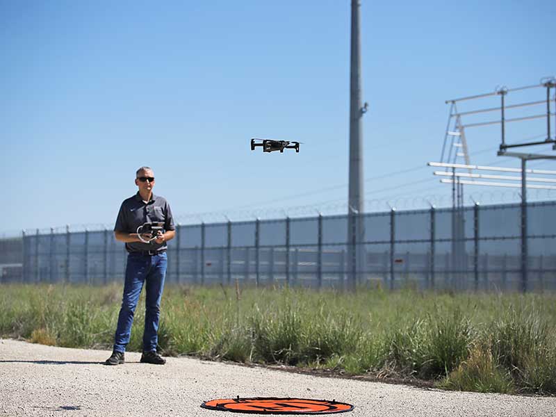 MidAmerican Employee landing a drone on the pad next to a substation