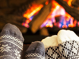 two sets of feet in wool socks with a fireplace burning in the background