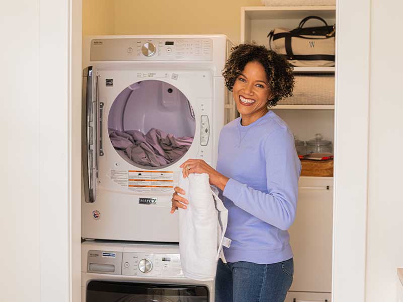 Woman folding clothes in front of a dryer