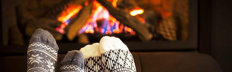 two sets of feet in wool socks with a fireplace burning in the background