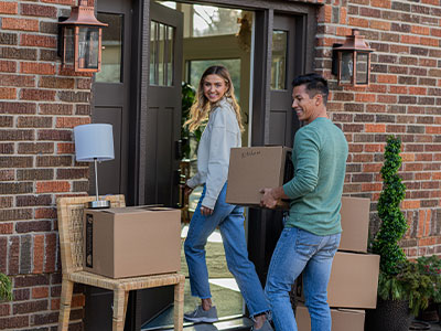 Young couple entering apartment carrying boxes